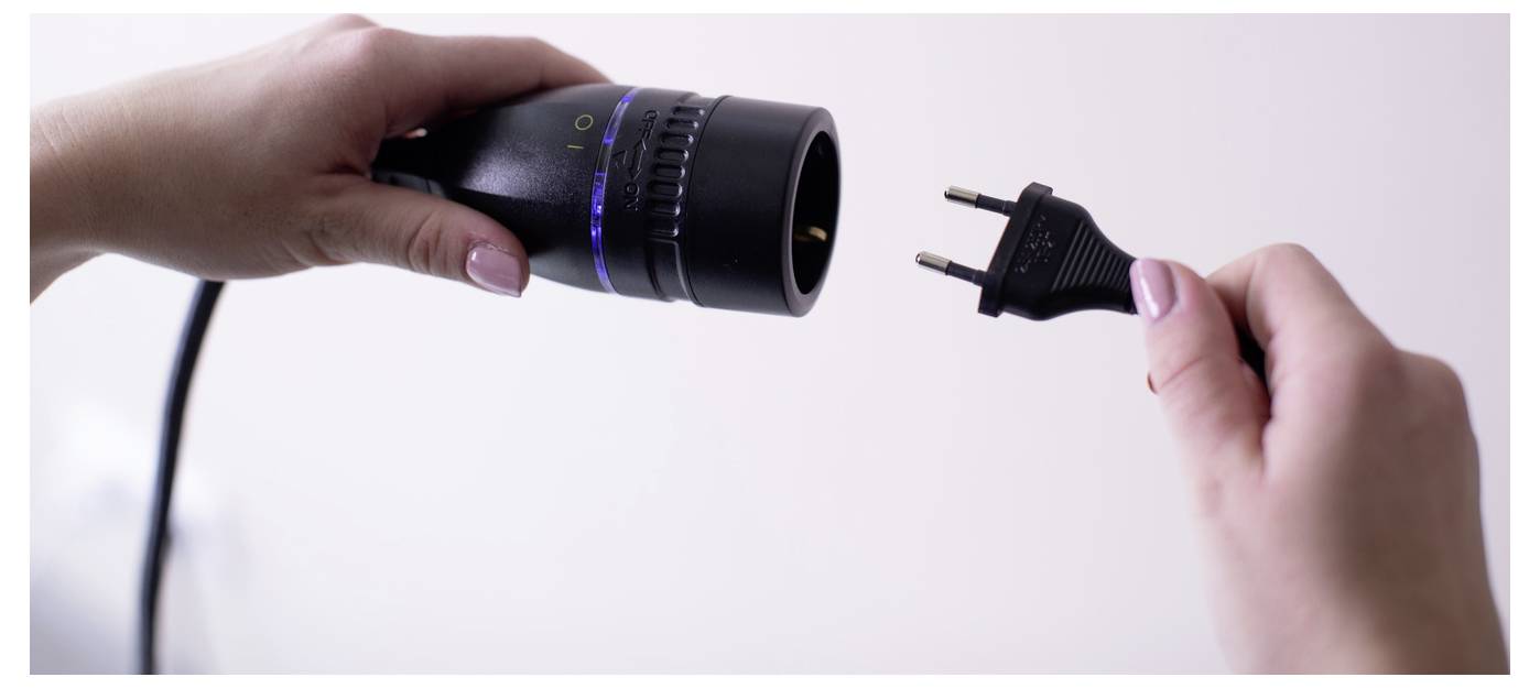 A kezek egy lecsatolt tápkábelt és a hozzá tartozó dugót tartanak, amely egy ki nem csatlakoztatott elektromos készüléket mutat.