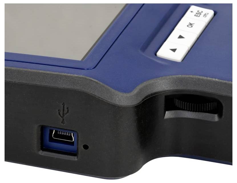 Egy hordozható eszköz közeli képe, amely egy USB-portot, oldalsó görgetőkereket és "ESC" és "OK" feliratú gombokat mutat.