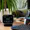 Egy asztal egy CO2-monitorral, amely 652 ppm-et mutat, egy PC-monitor mellett elhelyezve. Egy növény látható a háttérben.