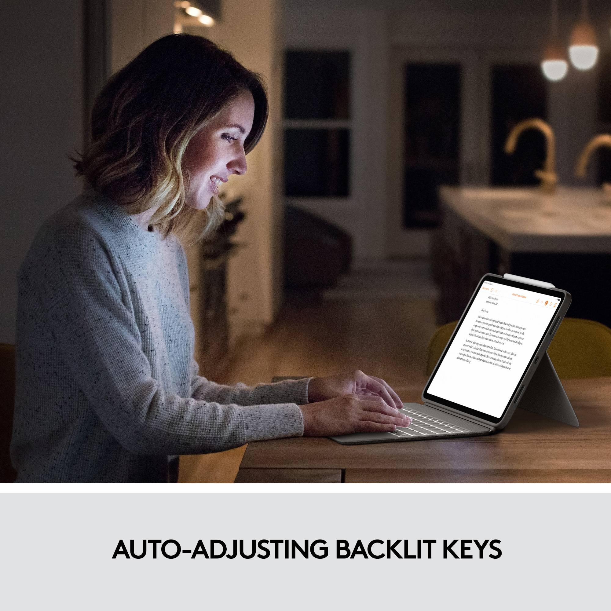 Egy nő ül egy asztalnál, és egy világító billentyűzetű tabletet használ sötét környezetben. Szöveg a képen: 'Automatikusan alkalmazkodó billentyűzet-háttérvilágítás'.