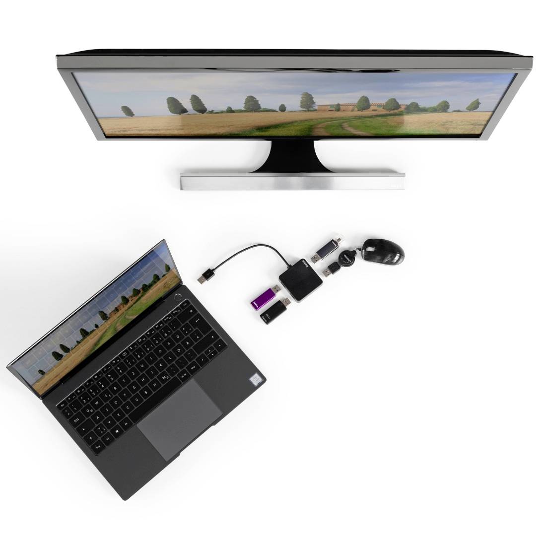 Laptop és monitor ugyanazzal a tájképpel; USB-elosztó köti össze a laptopot az egérrel és más eszközökkel. Felülnézet.