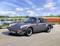 Egy ezüstszínű Porsche 911 halad egy vidéki úton. A háttérben egy folyó, tulipánmezők és hegyek láthatók.