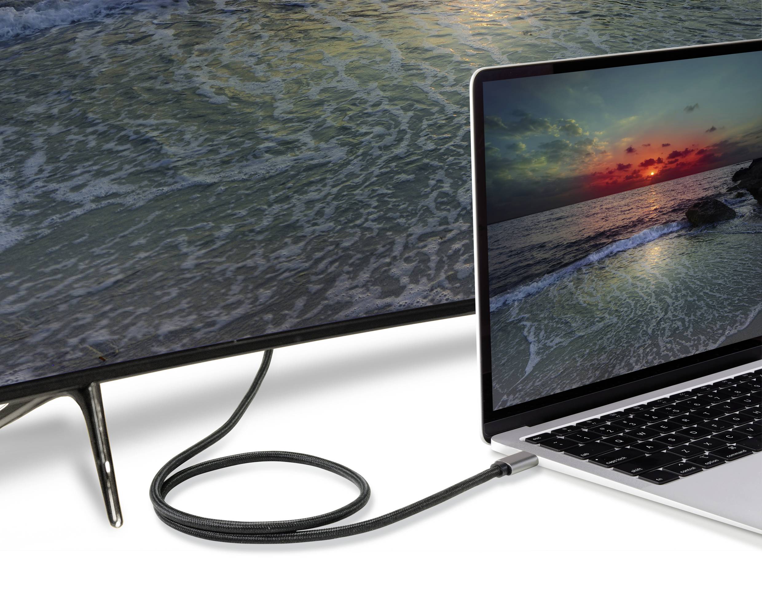 Egy laptop egy kábel segítségével csatlakozik egy nagy monitorhoz. Mindkét képernyőn egy tengerparti napnyugta képe látható.