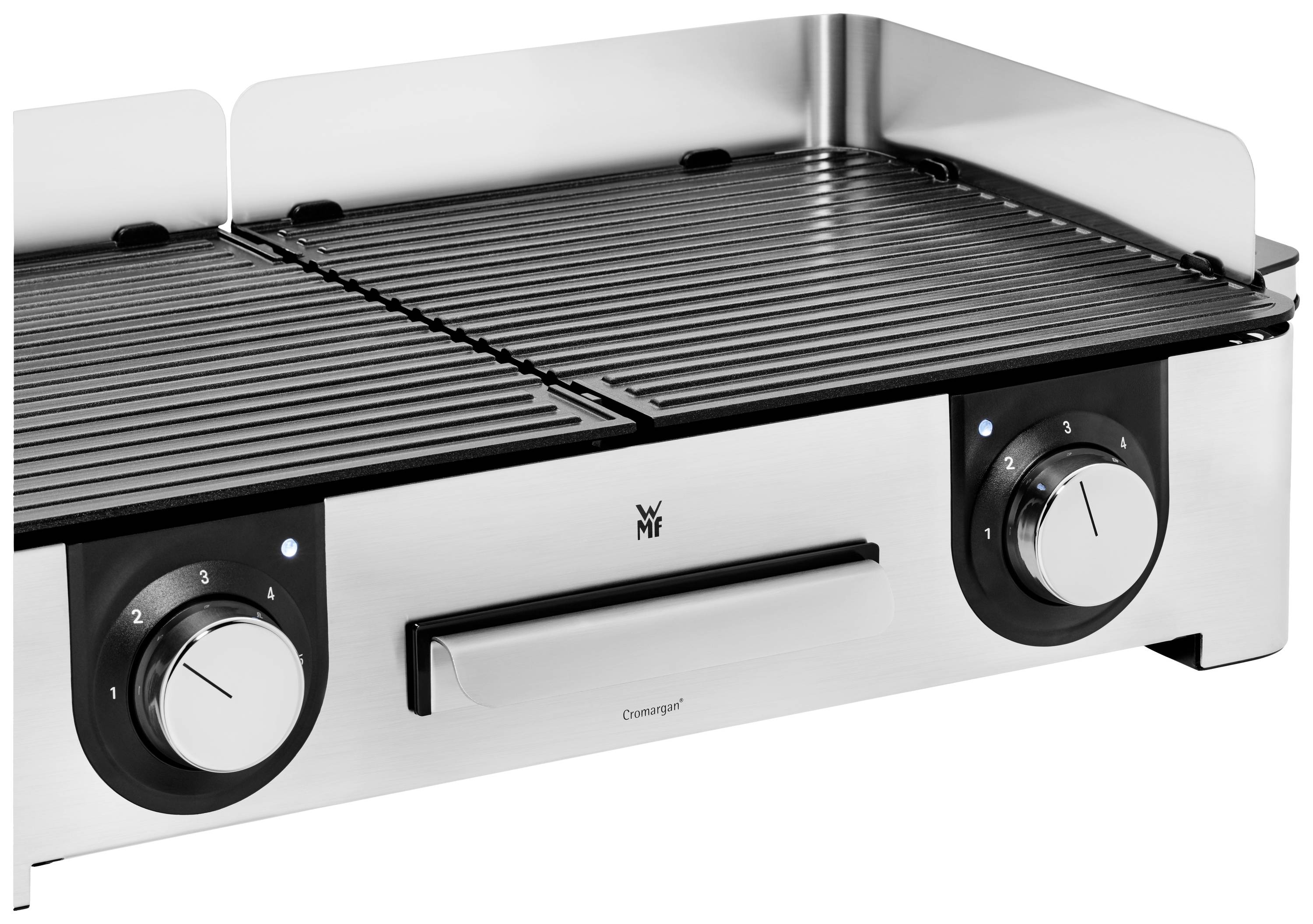 Egy ezüstszínű asztali grill két forgatógombbal a hőmérséklet beállításához. Középen a 'WMF' logóval megjelölve. Tökéletes grillpartikhoz.