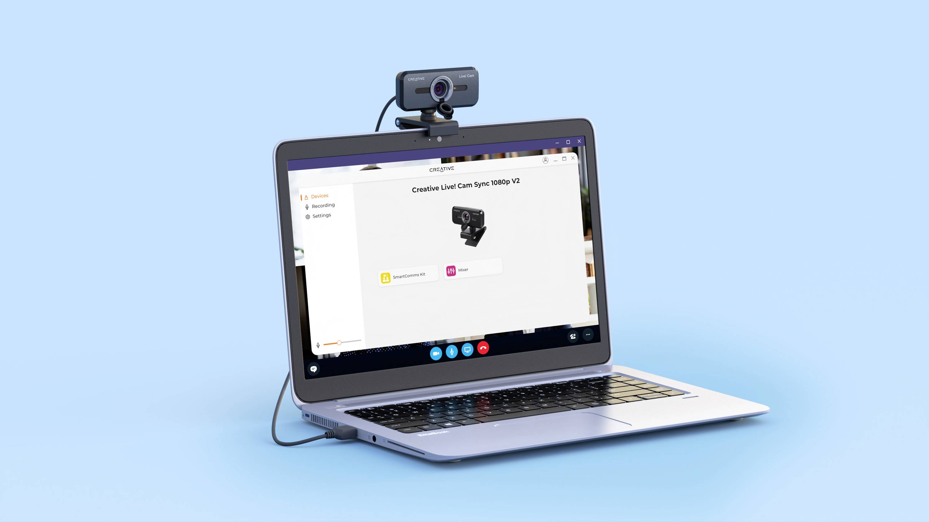 Egy laptop videókonferencia-szoftverrel megnyitva kék háttér előtt. A képernyő tetején egy webkamera van felszerelve.