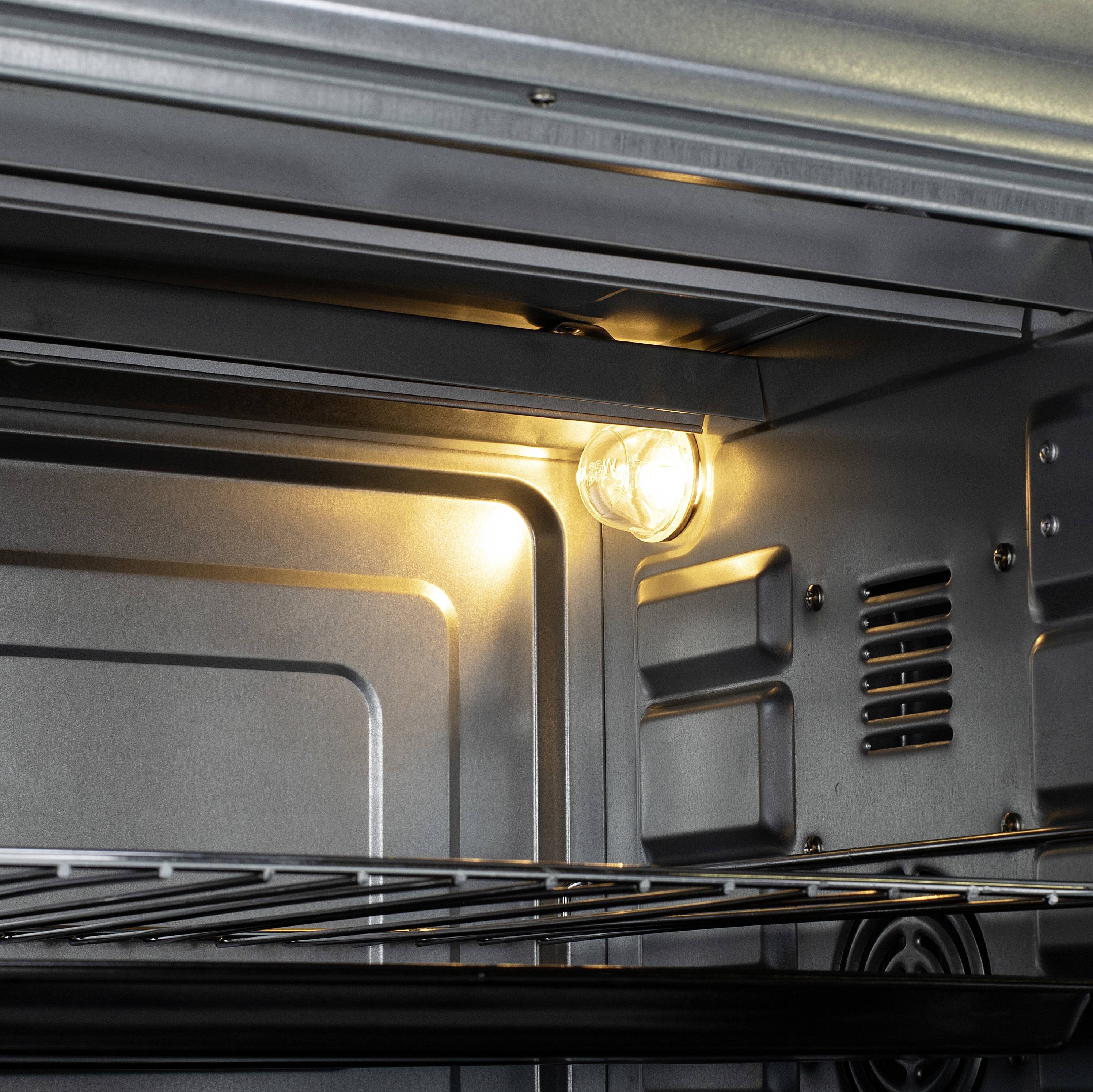 Egy fémből készült, világosan megvilágított, üres sütőbelső belső nézete, amelyen látható a rácsrács és a bal felső sarokban lévő izzólámpa.