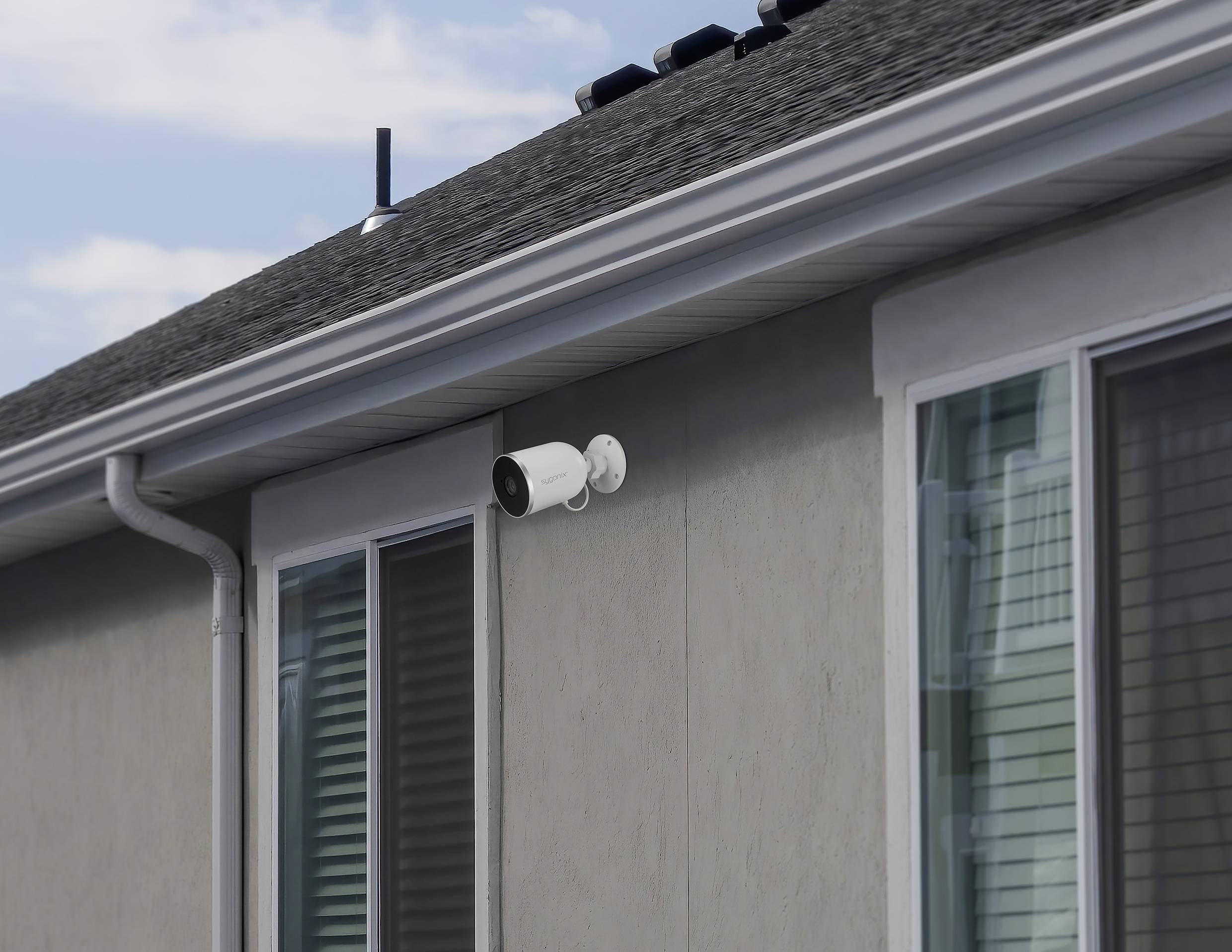 Egy ház külső nézete, amelyre a tetőereszalj alá telepített biztonsági kamera van felszerelve, amely hozzájárul az épület biztonságához.