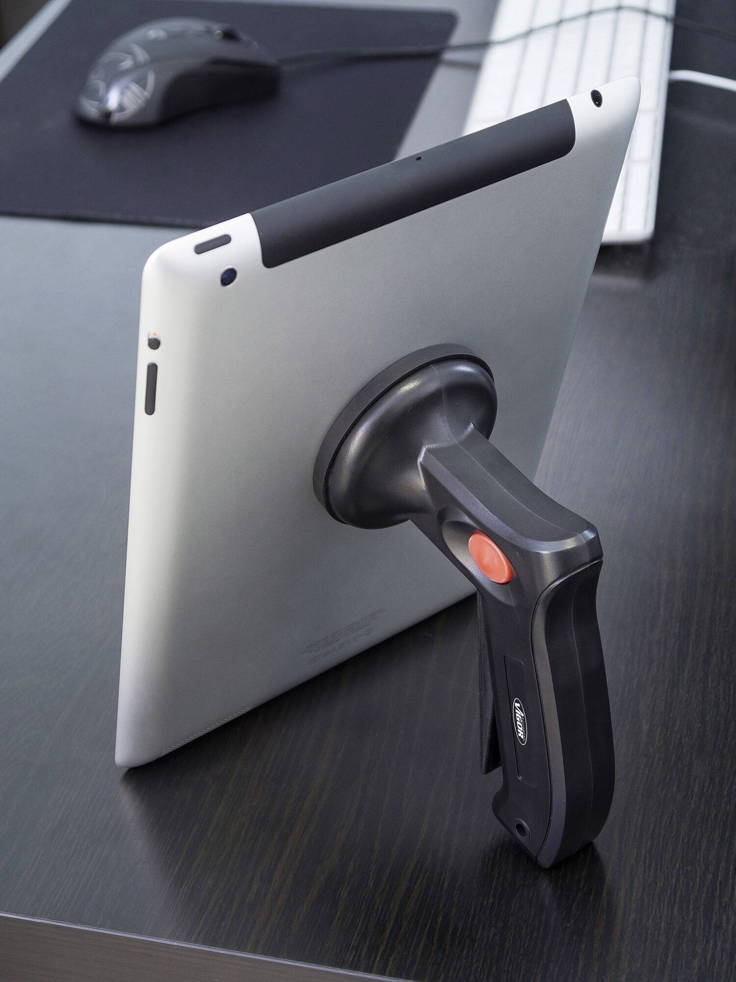 Egy tablet egy hátsó markolat segítségével támaszkodik egy asztalon. A háttérben egy billentyűzet és egy egér látható.