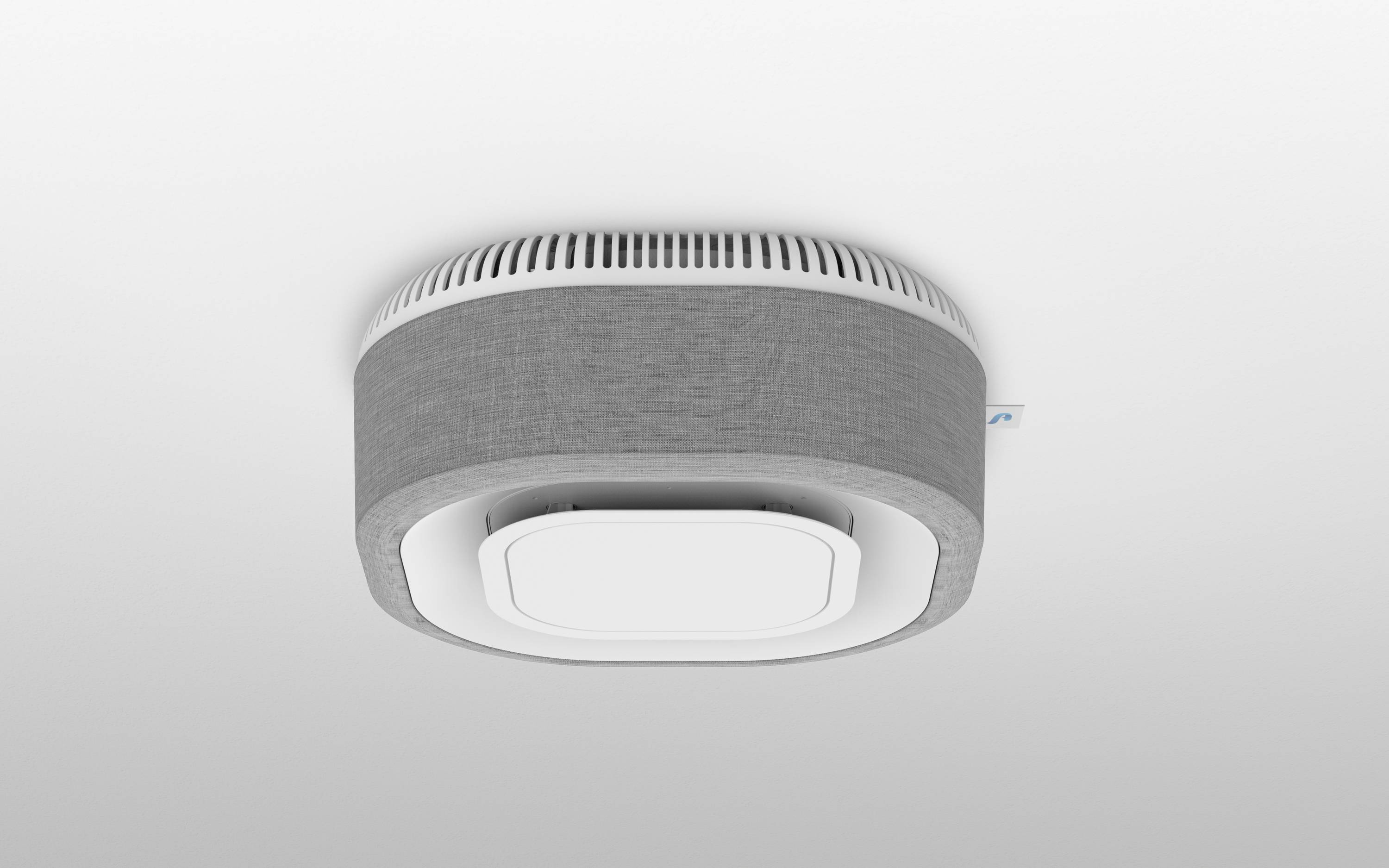 Egy szürke füstérzékelő van felszerelve egy helyiség mennyezetére. Modern, kerek dizájnnal rendelkezik fehér alsó résszel.