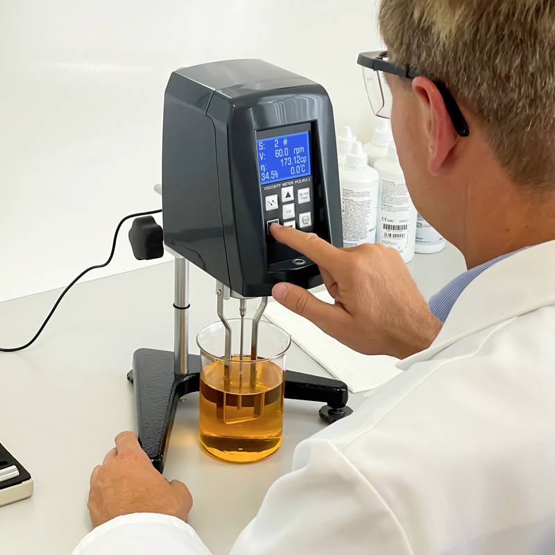 Egy tudós egy laboratóriumban viszkozimétert használ egy folyadék viszkozitásának mérésére. A mérési érték megjelenik a készülék kijelzőjén.