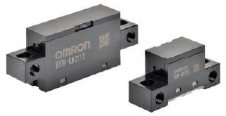 Két fekete elektronikai alkatrész, amelyeken az 'OMRON B5W-LB2112' felirat szerepel. Téglalap alakúak és szerelőnyílások vannak az oldalukon.
