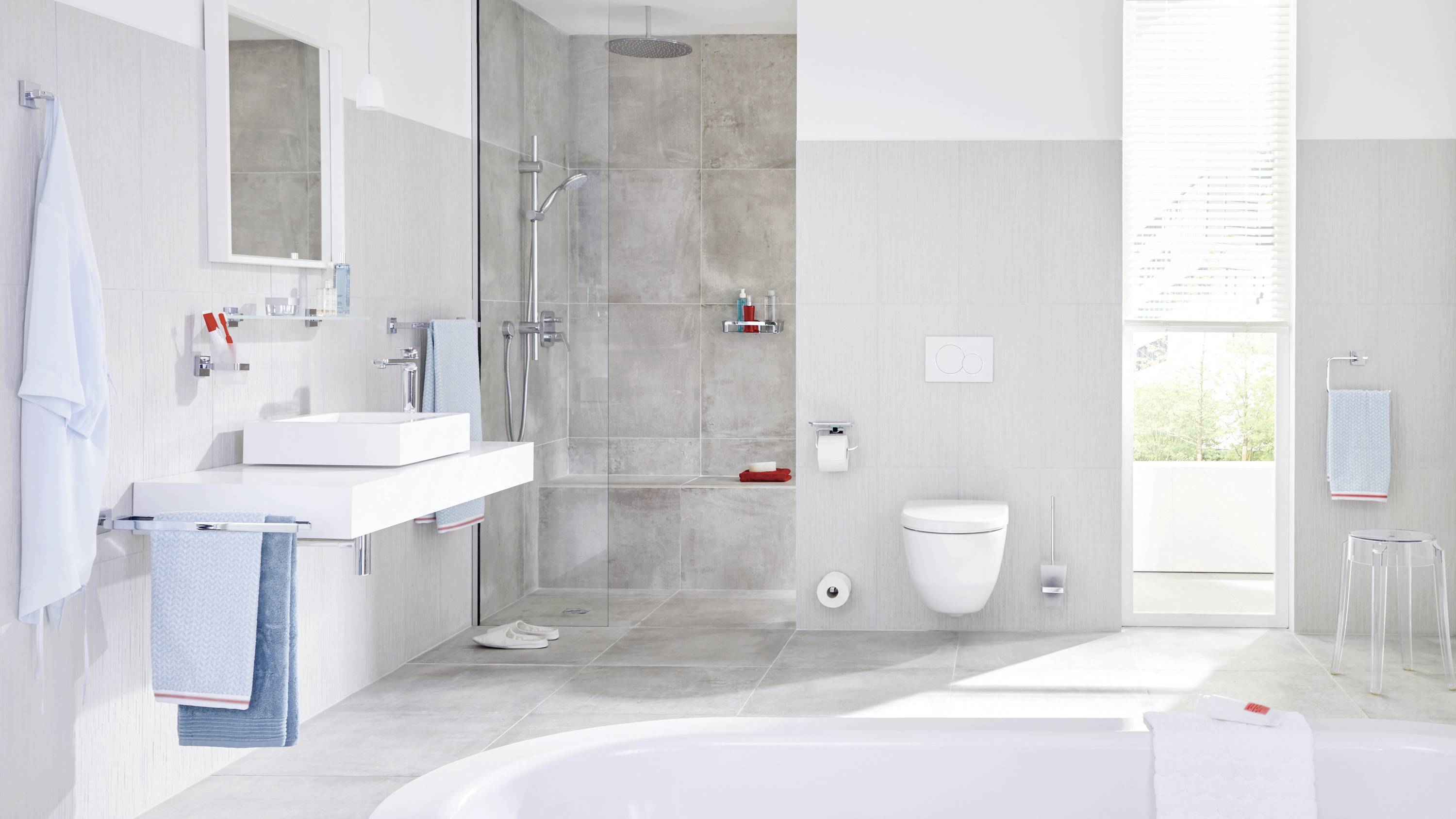 Modern fürdőszoba fehér káddarabbal, zuhannyal, mosdókagylóval és WC-vel. A világos színek és a letisztult design nyugodt hangulatot teremtenek.