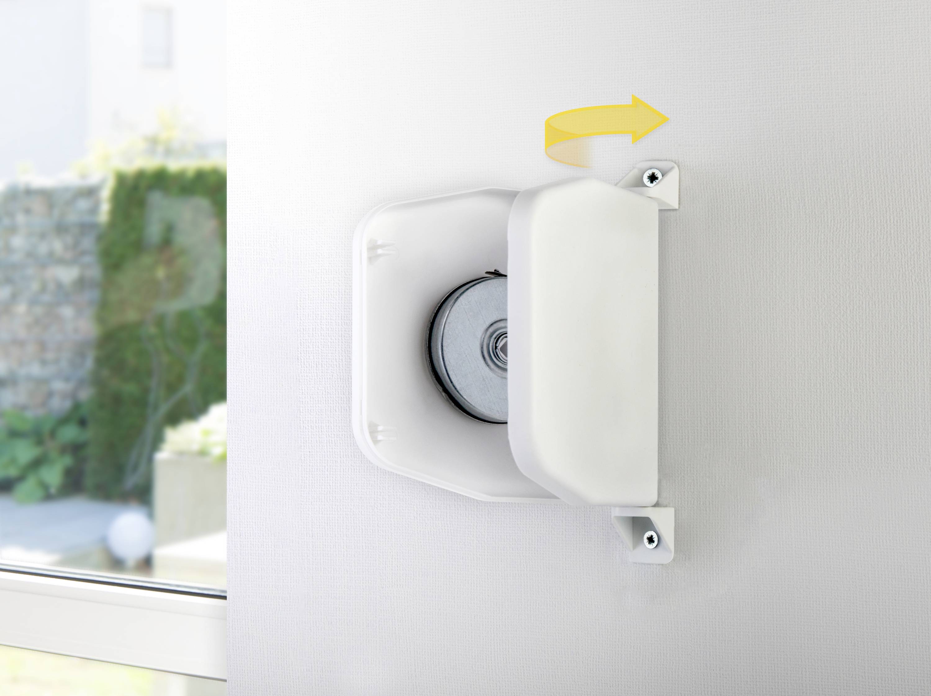 Egy sárga nyíllal jelzett fali redőnyszalag-feltekerő, amely a szalag felfelé történő mozgását mutatja.