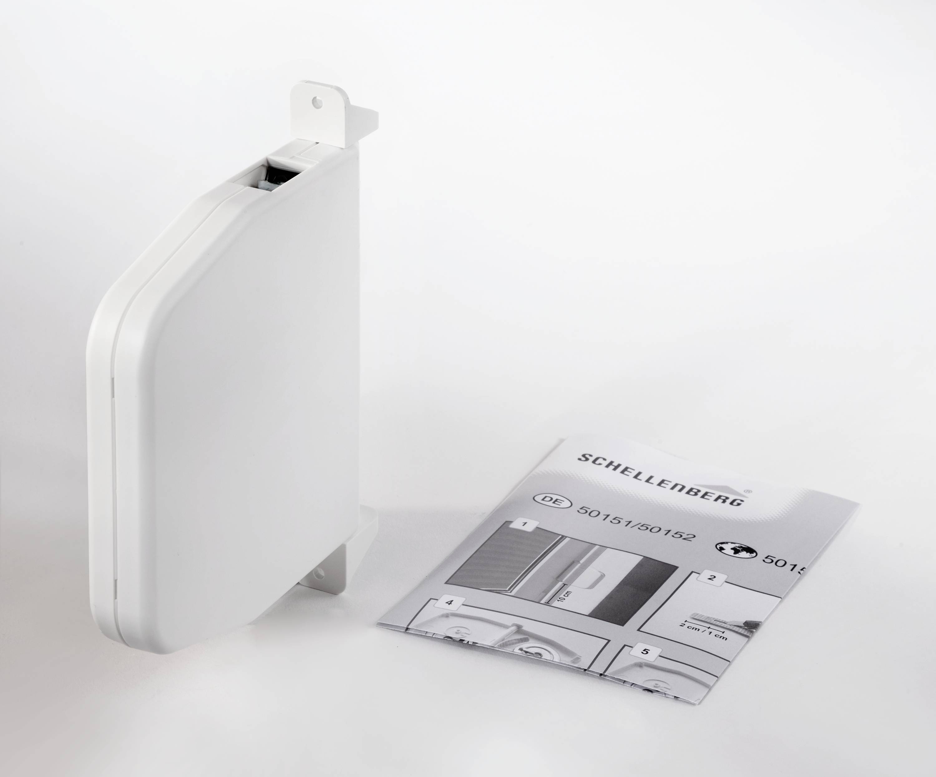 Fehér redőnytekercselő egy kinyitott használati útmutató mellett, amely a termék telepítésének lépéseit mutatja.