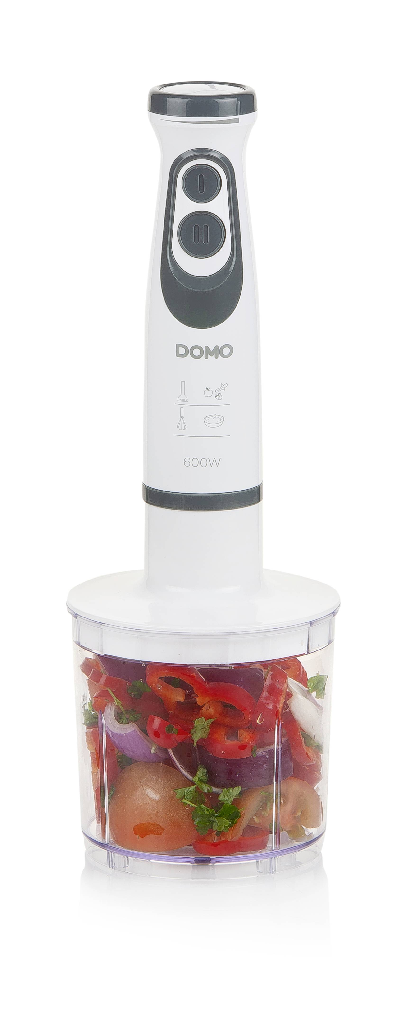 Egy botmixer egy átlátszó edénnyel, amelyben feldarabolt zöldségek, mint paradicsom, hagyma és paprika vannak.
