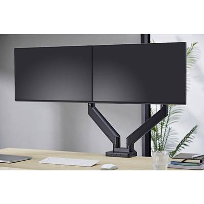 Két monitoros elrendezés flexibilis monitorkarokkal egy íróasztalon; a háttérben egy nagy ablak növényekkel.