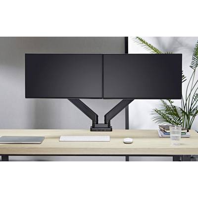 Két fekete lapos képernyő egy íróasztalon billentyűzettel és egérrel. Balra egy laptop, jobbra egy növény a háttérben.