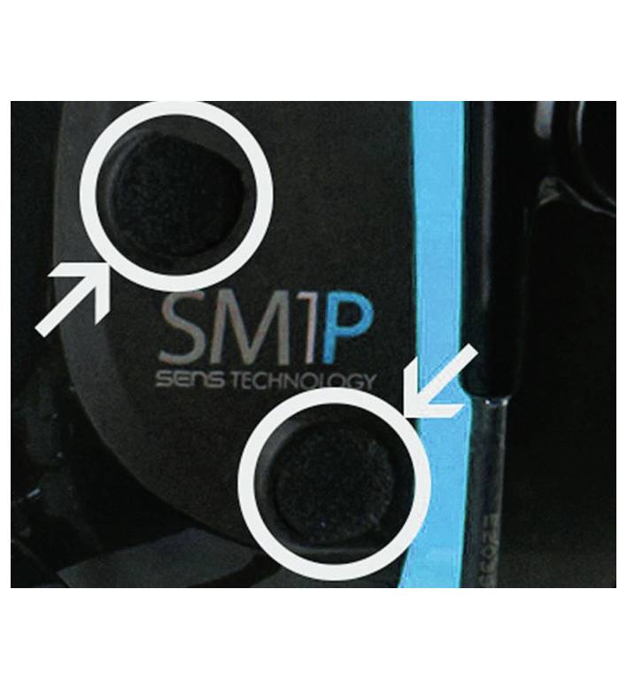 Két nyíllal ellátott köralakú gomb, a "SM1P SENS TECHNOLOGY" szöveg mellett, egy sötét felületen kék csíkkal.