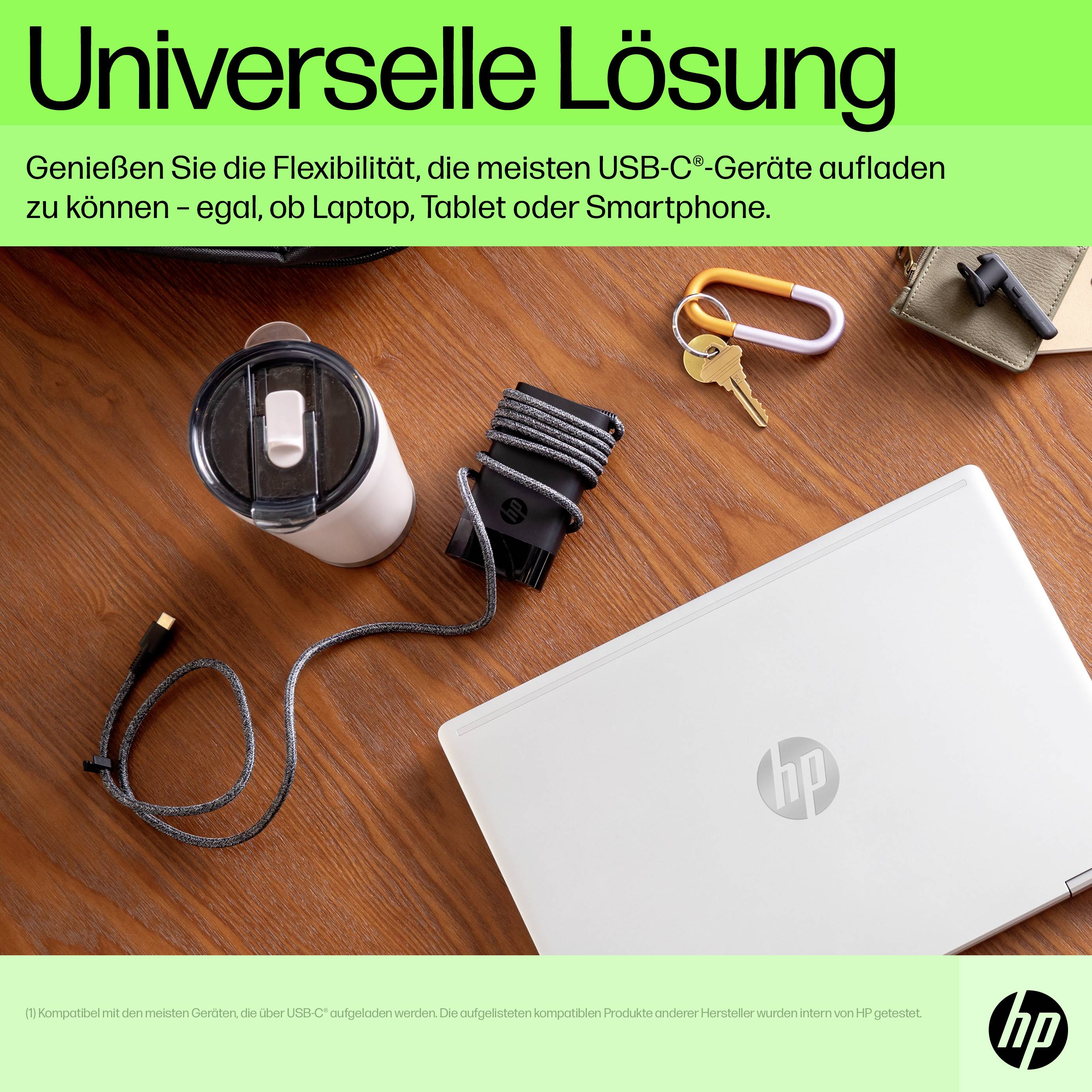 Laptop az asztalon, körülvéve kulcsokkal, ivópalackkal és kábelekkel. Felcímsor: 'Univerzális megoldás', hirdeti az USB-C-s töltést.