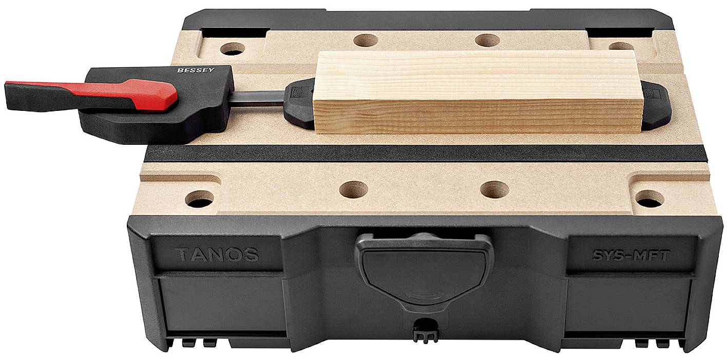 Fadarab egy munkadarabtartóra rögzítve, biztosítva egy szorítóval, fekete és márványos háttér előtt.