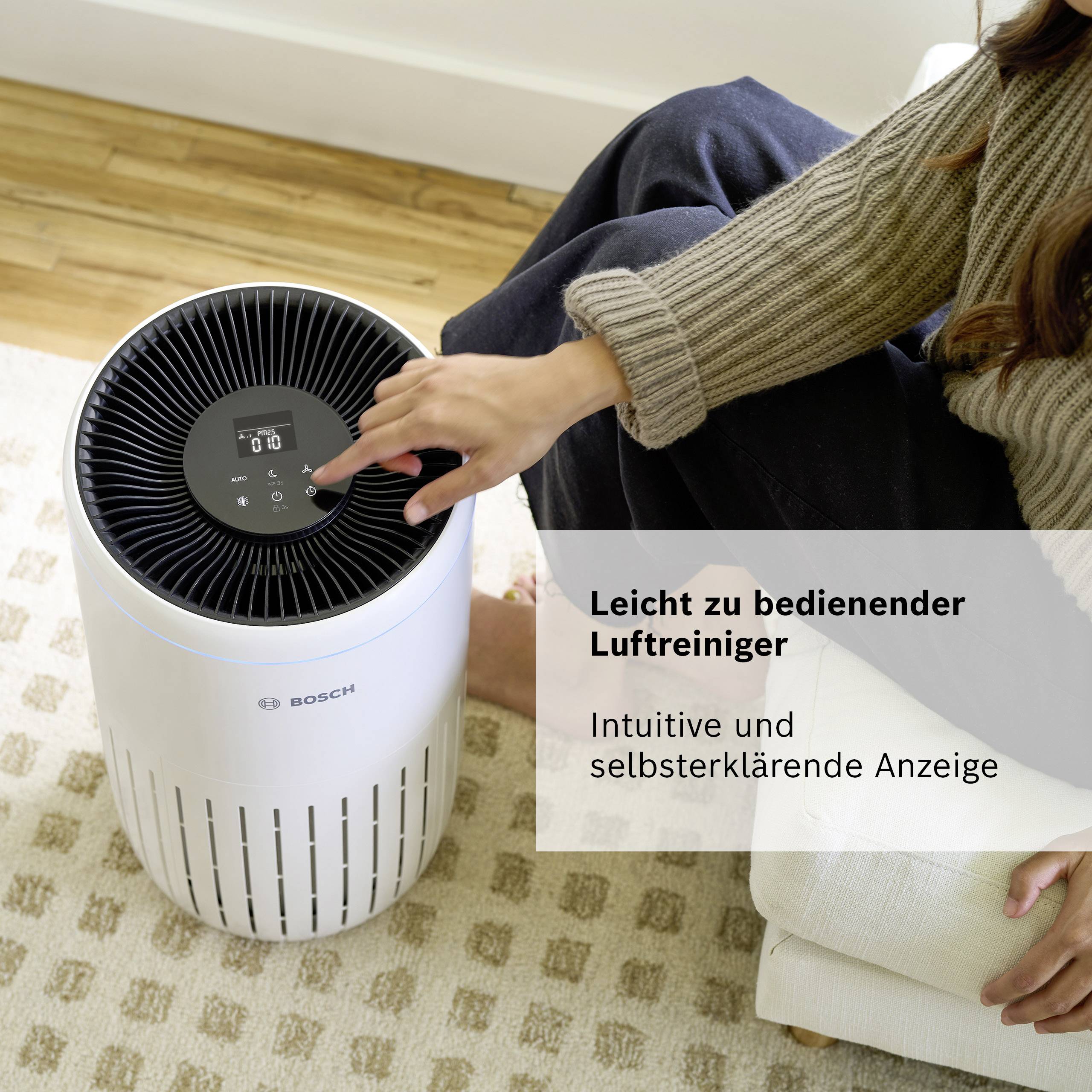 Egy nő ül egy légtisztító mellett a padlón. Mellette áll: 'Méretek: Magasság: 500 mm, Szélesség: 291 mm, Mélység: 291 mm'.