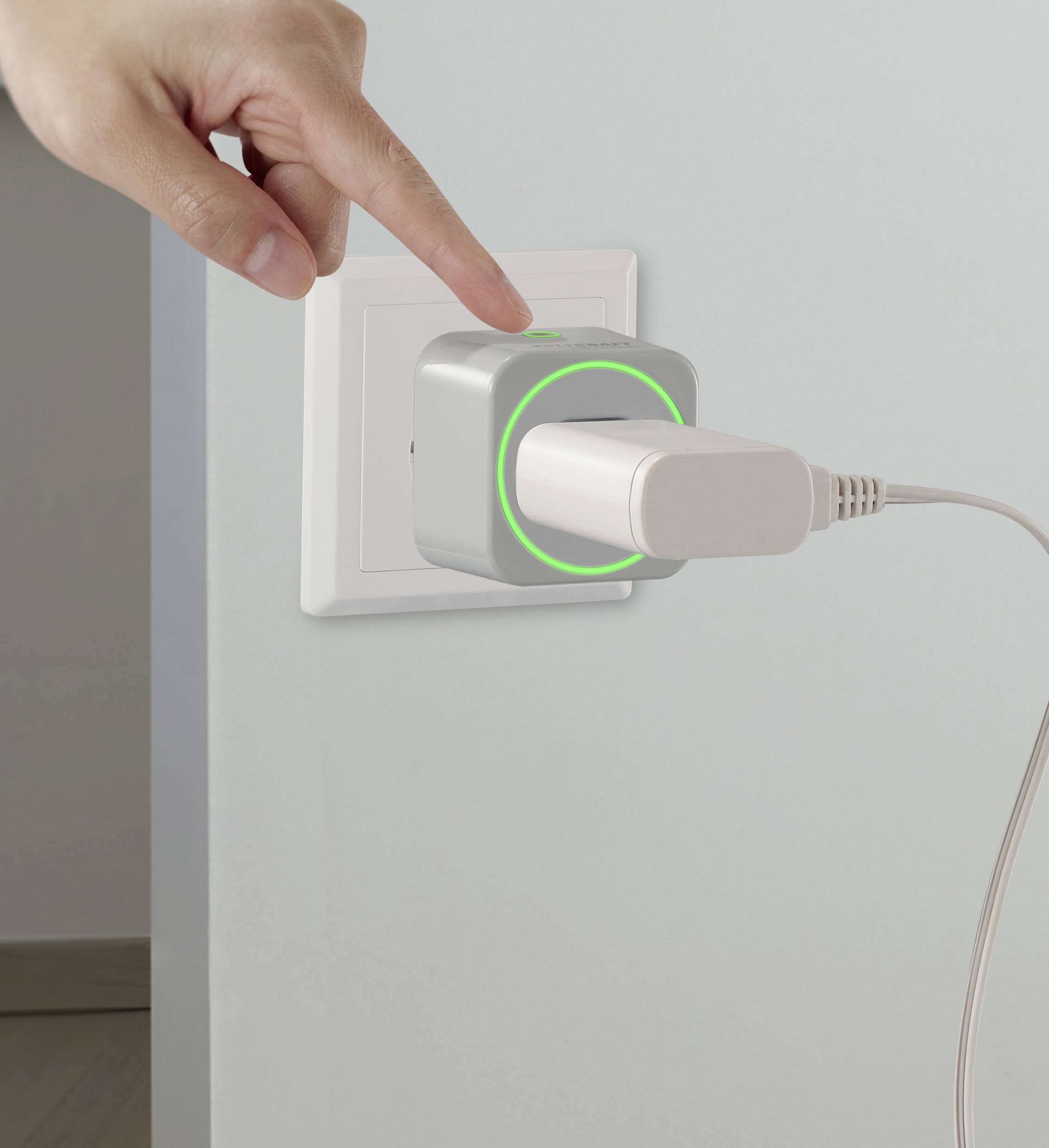 Egy kéz egy konnektorba dugott adapterre mutat, amelyhez egy USB-kábel csatlakozik. Az adapter zöld fénnyel világít.