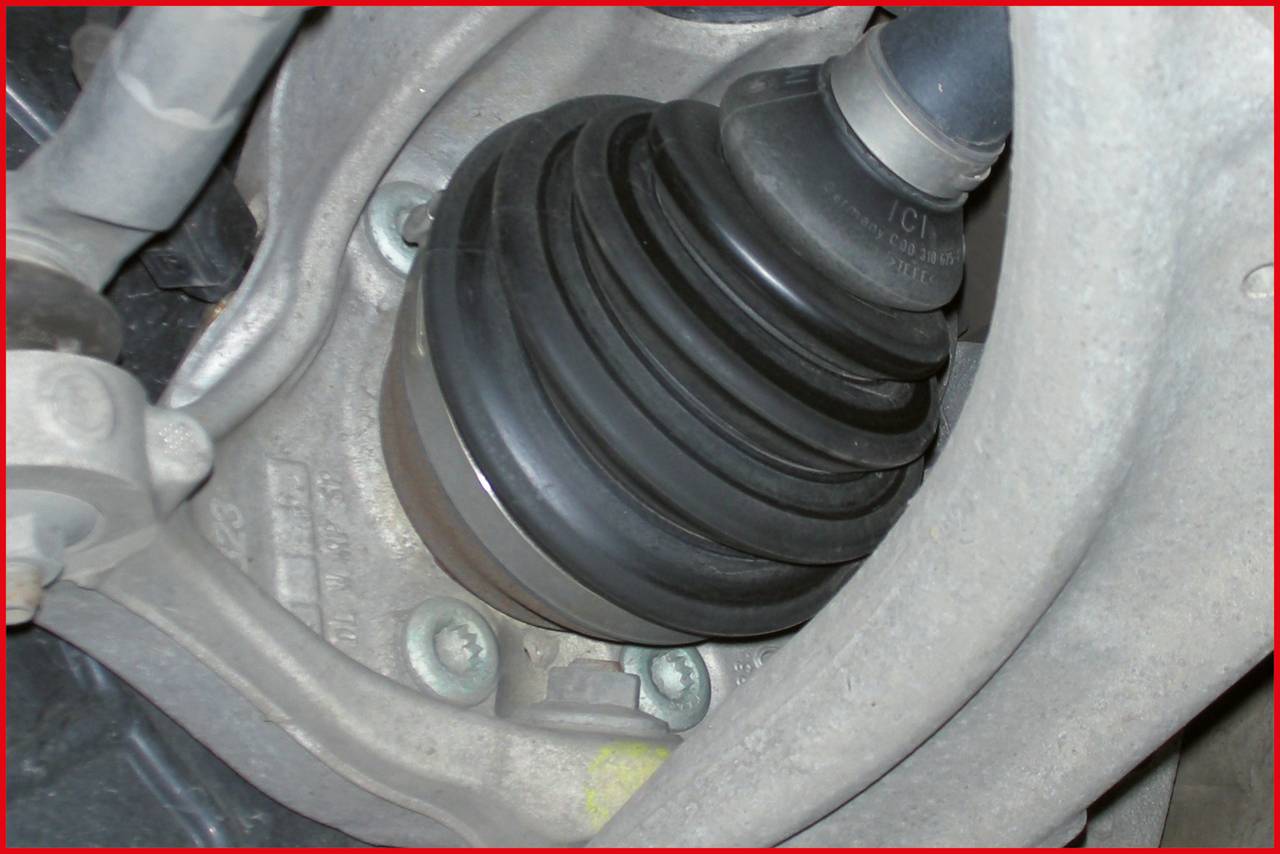 Egy autó hajtáslánc-csatlakozójának közeli felvétele, fémalkatelemek által körülvéve. A kép a járműrendszer mechanikai kapcsolatát mutatja.