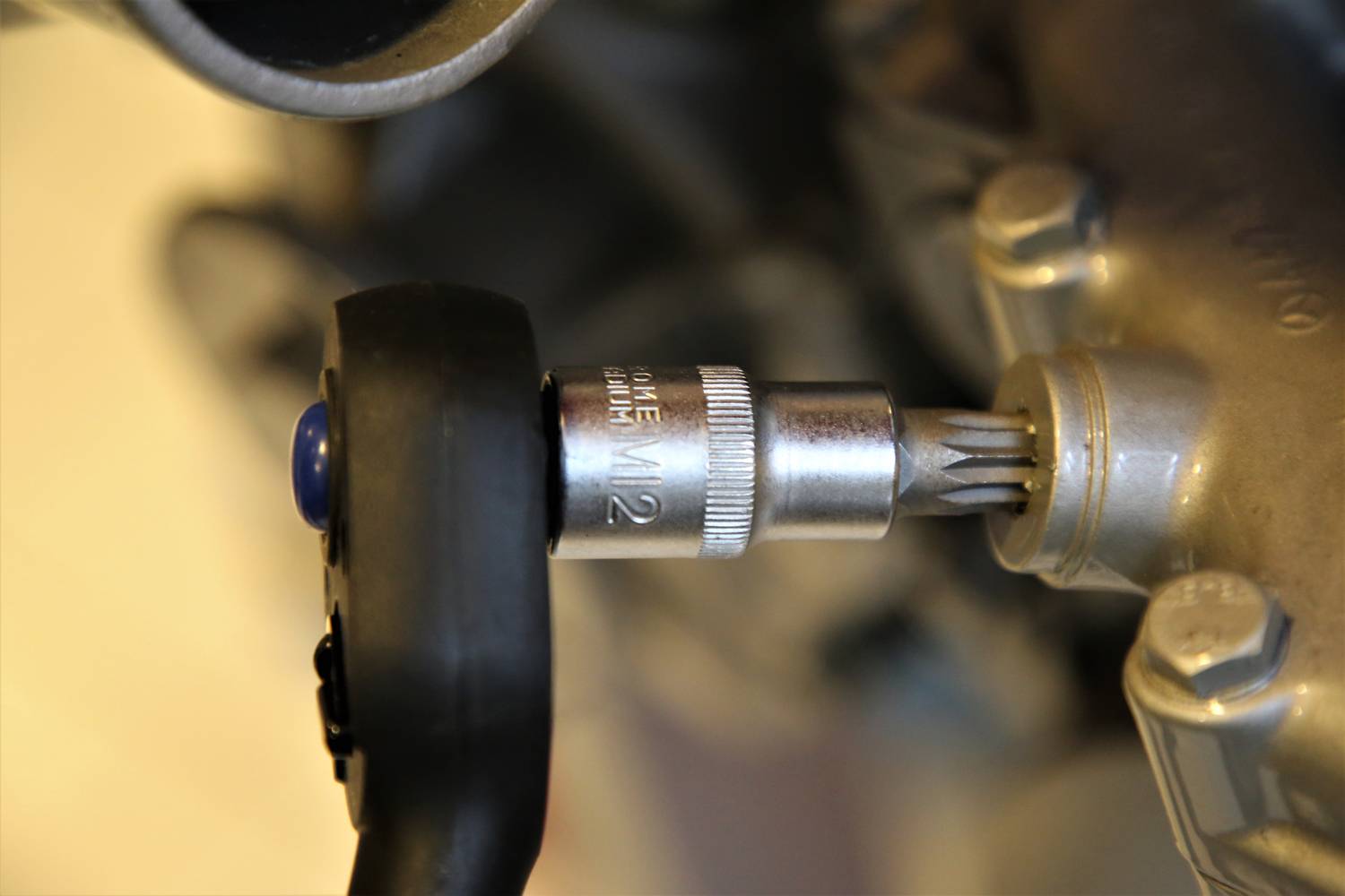 Egy csavarbehajtó közelképe, amint éppen meghúz egy csavart. A felvétel a szerszám alapját mutatja egy fémdarab megmunkálása közben.