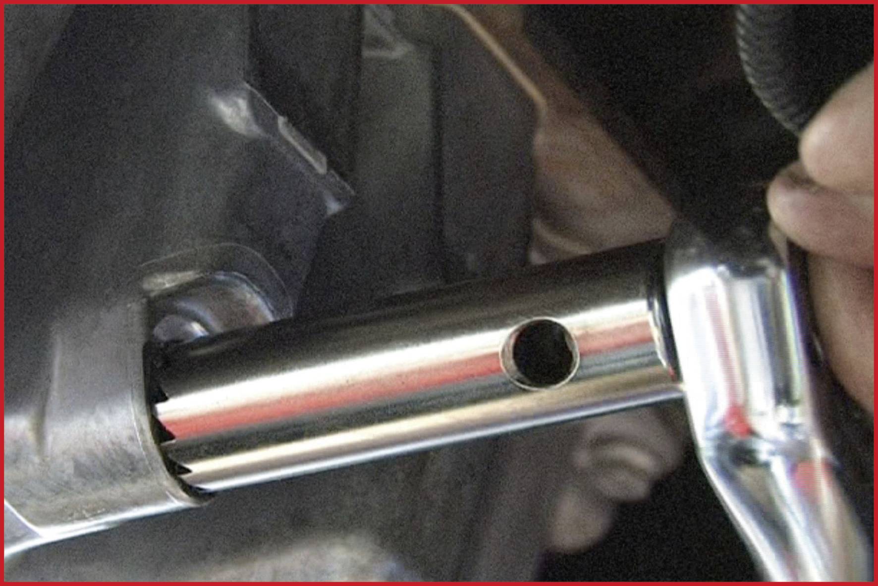 Egy kéz egy villáskulcsot használ egy fémrúd vagy csatlakozóelem rögzítéséhez vagy karbantartásához egy gépen.