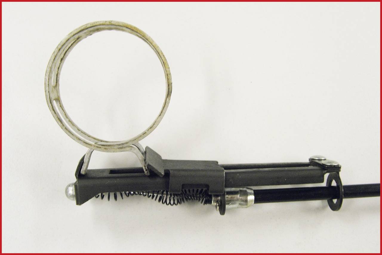 Fémes, mechanikus tárgy, amelynek egyenes nyélhez rugalmas, köralakú elem csatlakozik, valószínűleg egy szerszám része.