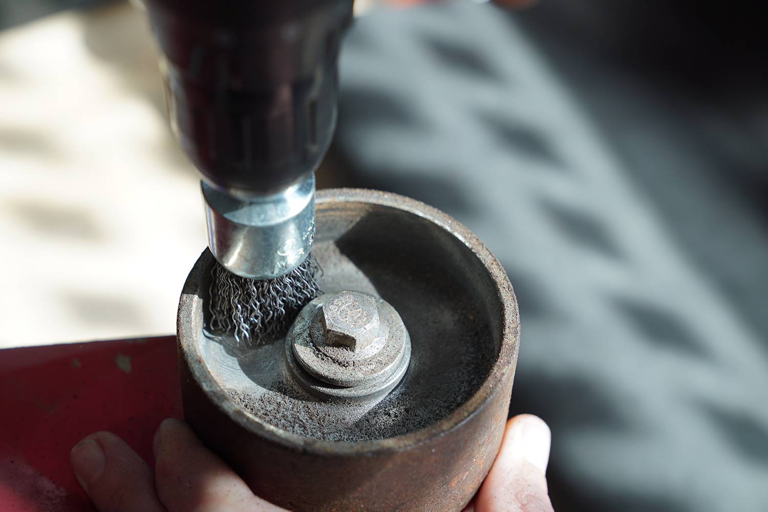 Egy fémkefe, amely egy fúrógépre van szerelve, megtisztítja egy hengeres fémtárgy belső felületét.