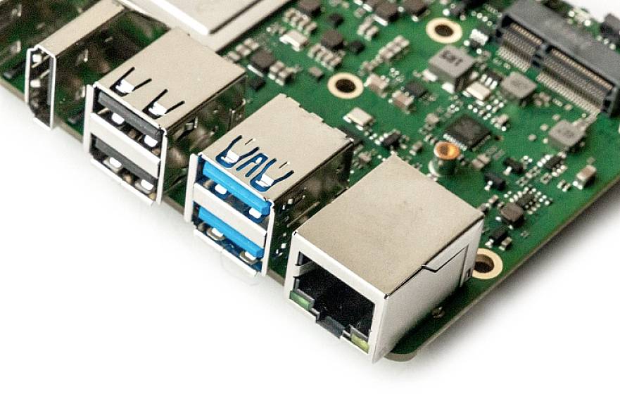 Egy nyomtatott áramkör (PCB) közeli felvétele, amely több USB-csatlakozót és egy Ethernet-portot mutat. Elektronikai alkatrészek és csatlakozók láthatók rajta.