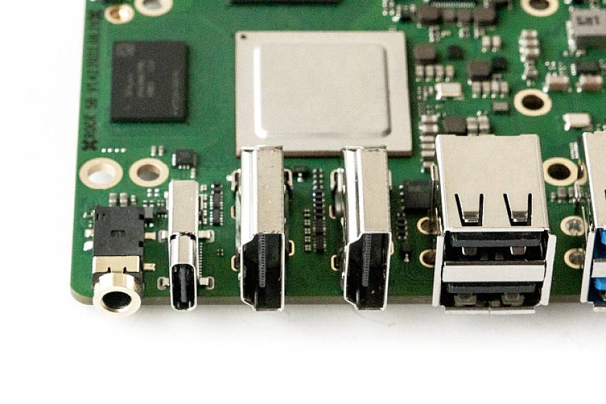 Közeli felvétel egy zöld nyomtatott áramköri lapról, amelyen több csatlakozó, köztük USB-portok és egy audiabemenet látható.