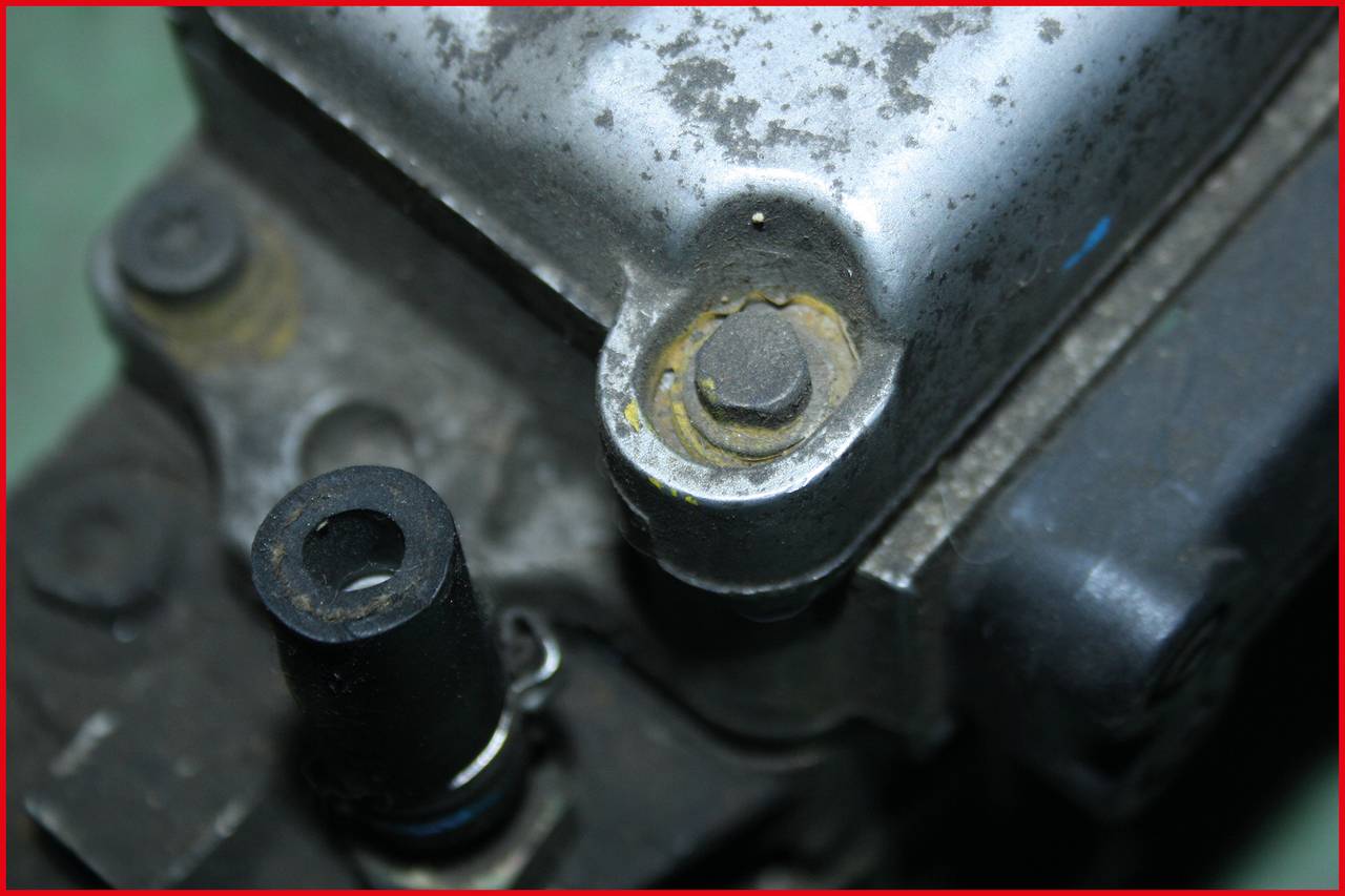 Fémdarab közeli képe csavarokkal és kopásnyomokkal. Valószínűleg egy mechanikai vagy elektronikai eszköz alkatrésze.