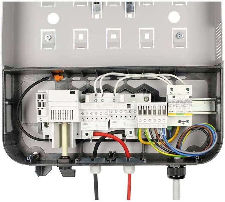 Egy nyitott biztosítékszekrény, amelyben különböző színű kábelek, kapcsolók és csatlakozók láthatók, bemutatva az elektromos bekötéseket.