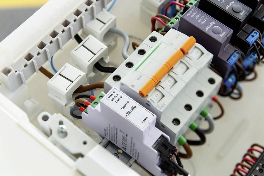 Elektromos biztosítéktábla több kapcsolóval és vezetékkel, komplex elrendezésben mutatja az adott elektromos alkatrészeket.