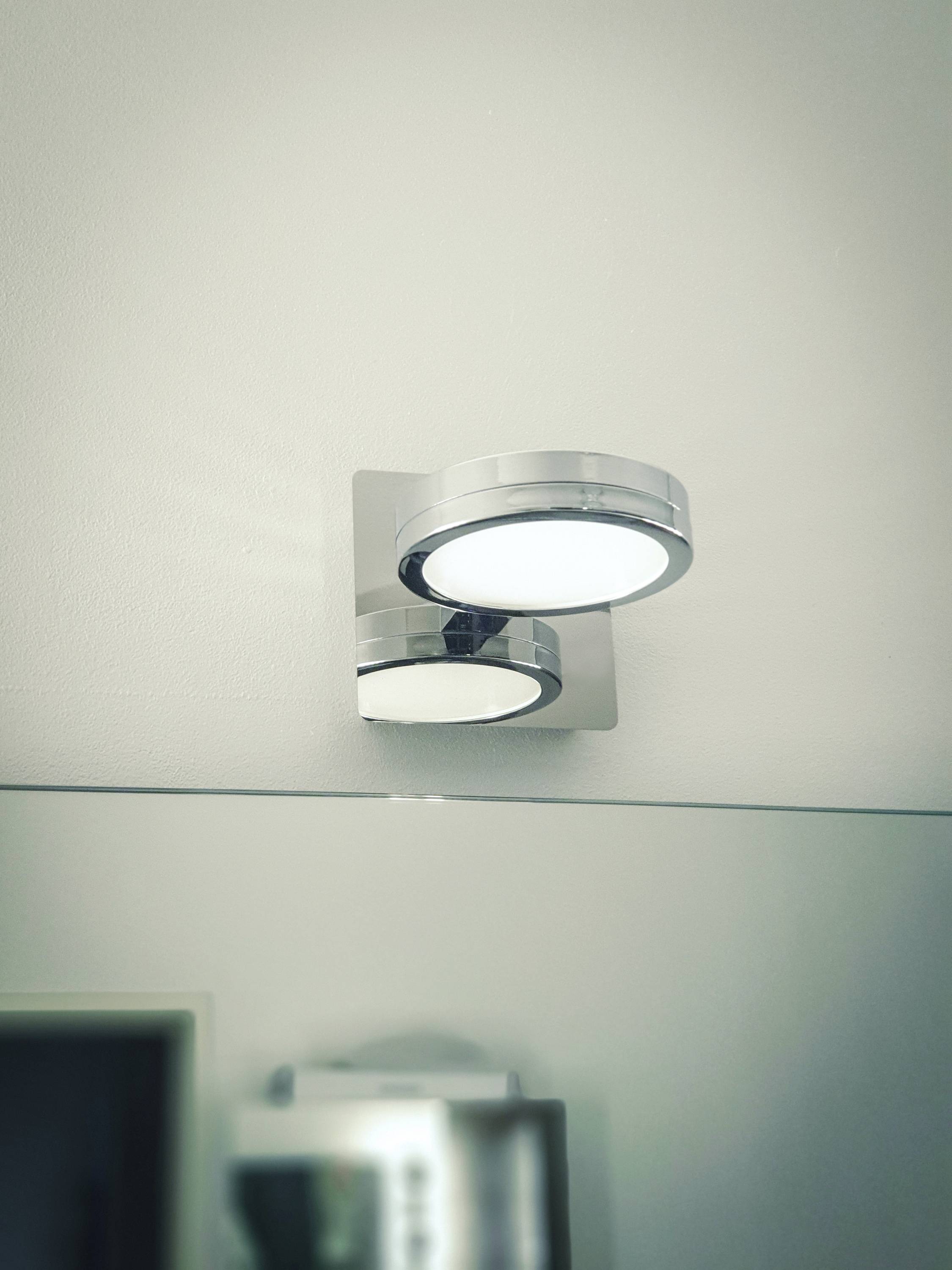 Egy modern, hengeres mennyezeti lámpa fémből, amelynek világos fénye lefelé irányul, fehér mennyezetre szerelve.