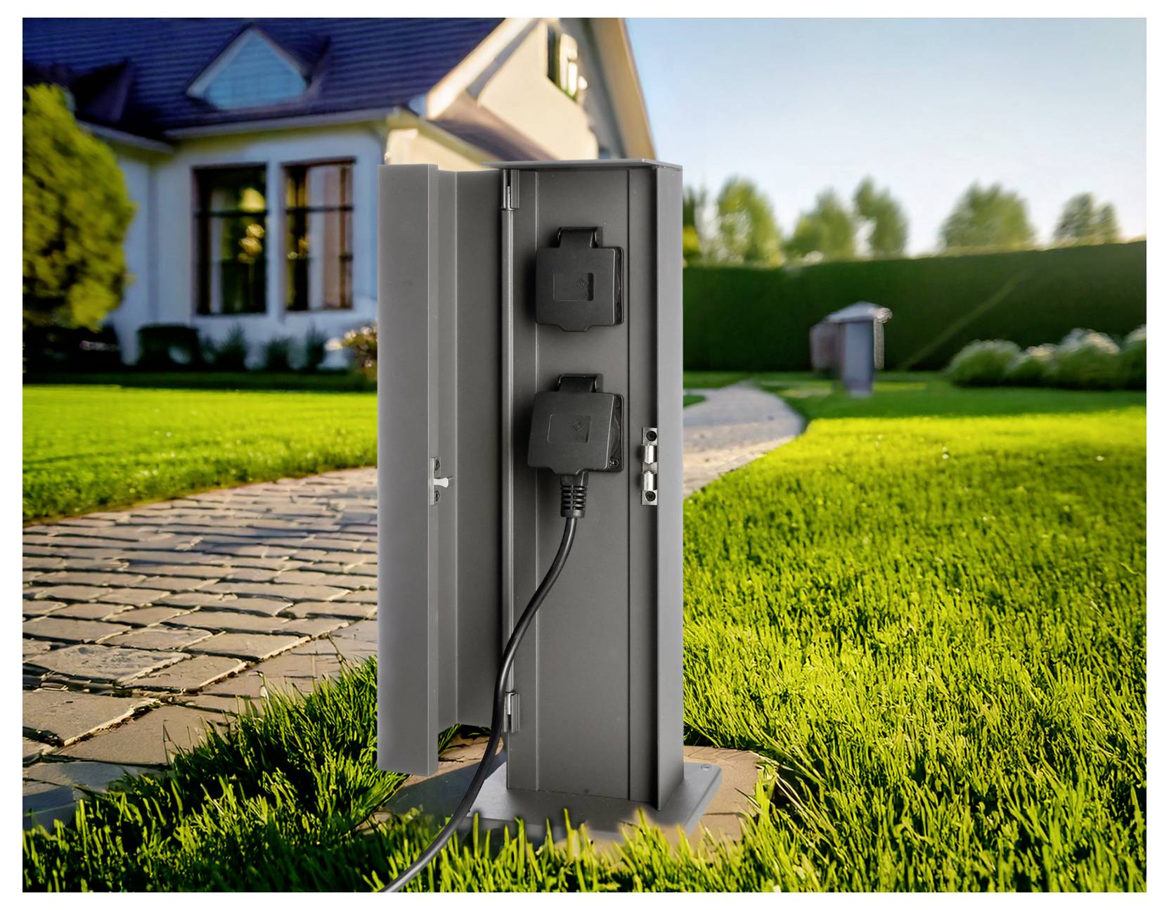 Időjárásálló kültéri elektromos oszlop, csatlakoztatott készülékkel és kábellel, egy ház mellett, gyepen és kőburkolatú járda közelében.