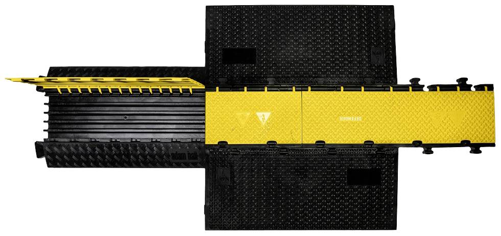 Sárga kábelhíd levehető fedéllel, fekete alapzaton, védi a kábeleket nyilvánosan hozzáférhető területeken.