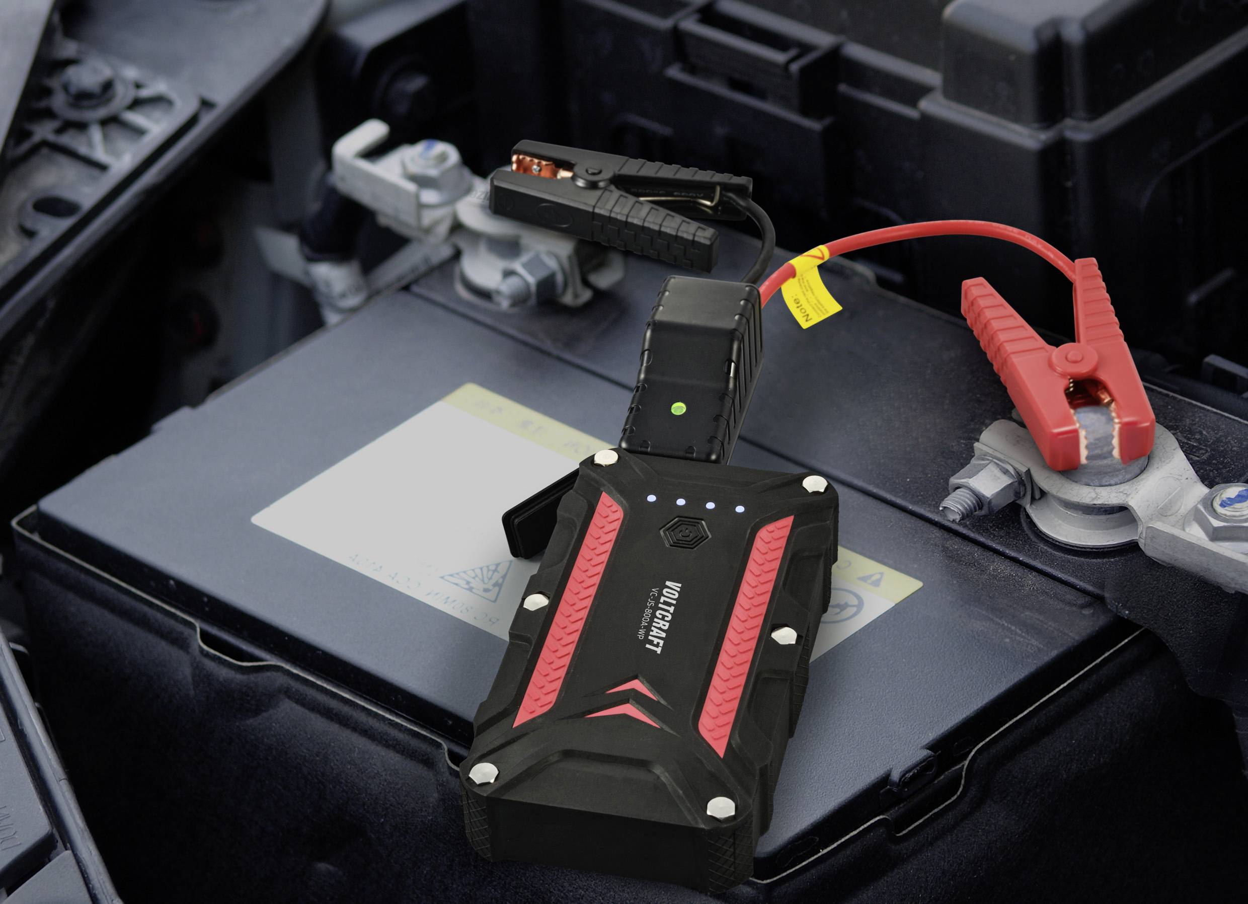 Indítókábel és segédindító kábel csatlakoztatva van egy autóakkumulátorhoz. A készülék egy zöld jelzőlámpát mutat.