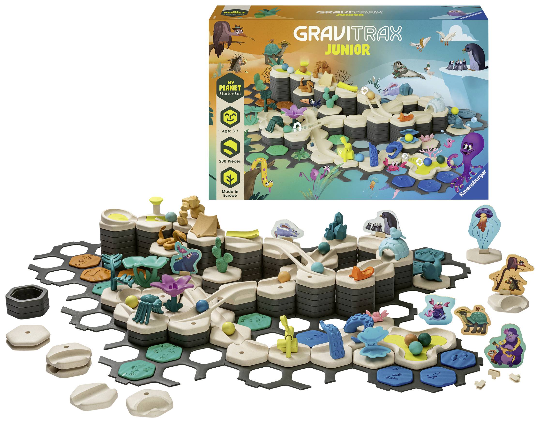 Egy GraviTrax Junior játékszett különböző pályaelemekkel és figurákkal. A háttérben a színes csomagolás látható.