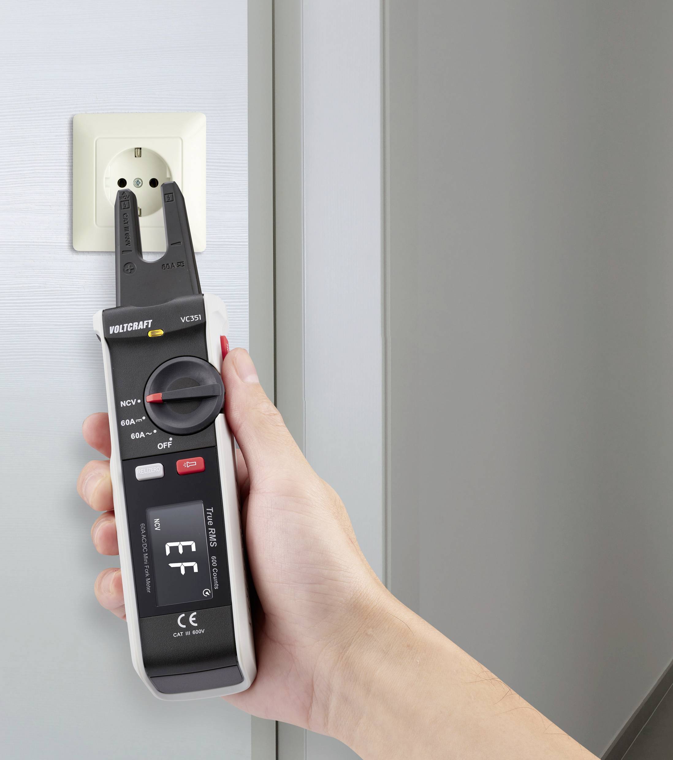 Egy kéz elektromos vizsgálókészüléket tart egy csatlakozóaljzatnál. A készülék 'EF' állapotot jelez. Különböző üzemmódok választhatók.