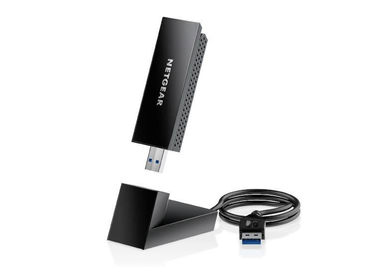 Egy fekete Netgear USB WLAN-adapter állvánnyal és USB-kábellel. Az adapter a Netgear logót mutatja és enyhén döntött szögben áll.