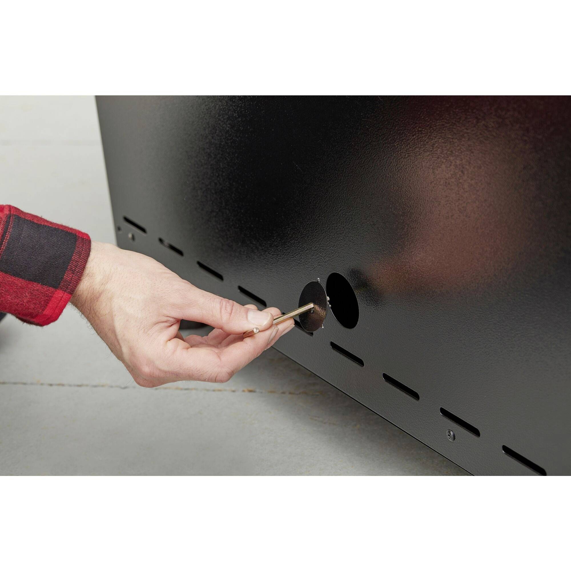 Egy kéz kulcsot helyez egy zárba egy fekete felületen.