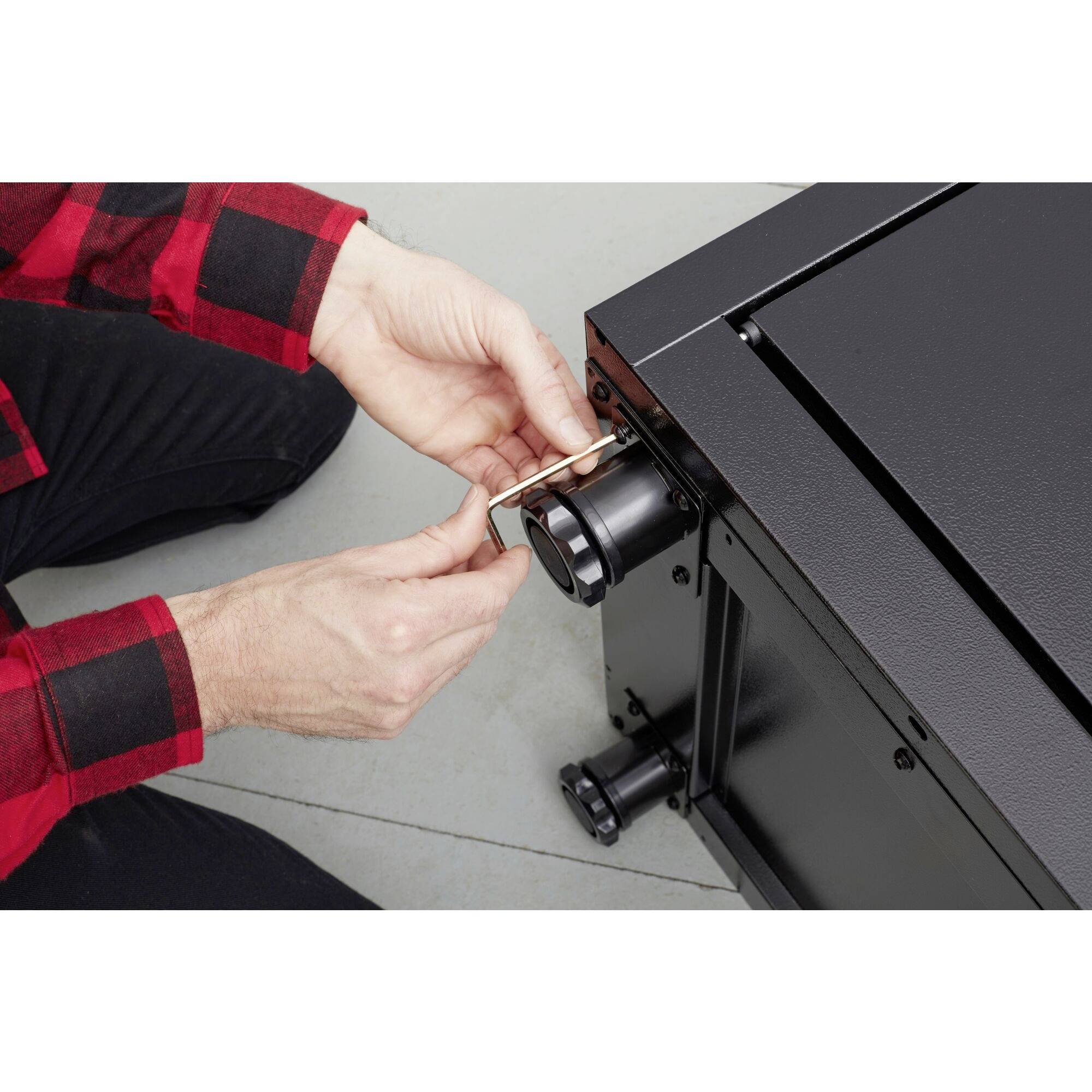 Egy személy egy biztonsági szalagot húz le egy fekete eszközről, amely valószínűleg egy szerszám vagy javítandó, illetve karbantartandó tárgy.