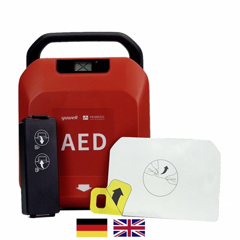 Egy piros AED-készülék használati útmutatóval. Mellette papírlap német és brit zászlókkal, amelyek a nyelvi opciókat jelzik.