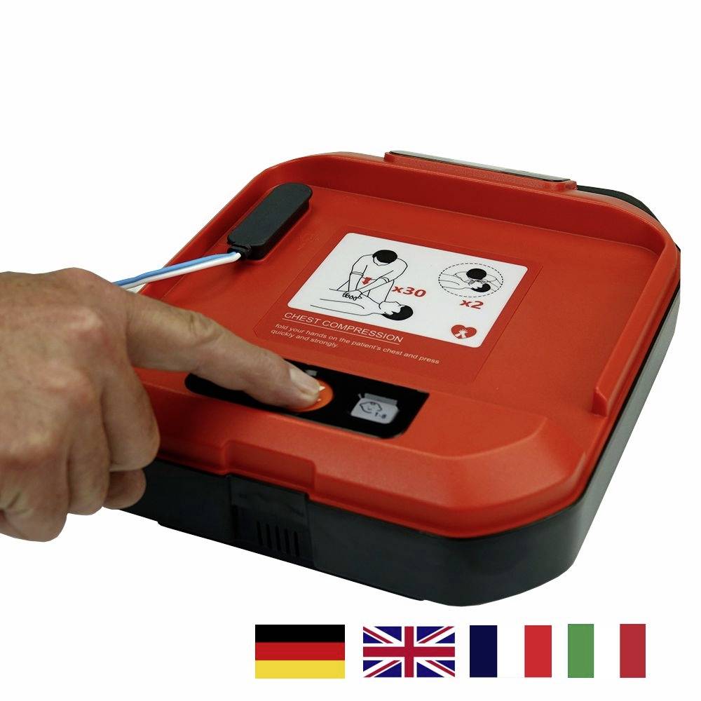 Egy kéz megnyomja egy defibrillátor gombját. A készülék piros és mellkasi kompresszióra vonatkozó utasításokat mutat. Zászlók lent.