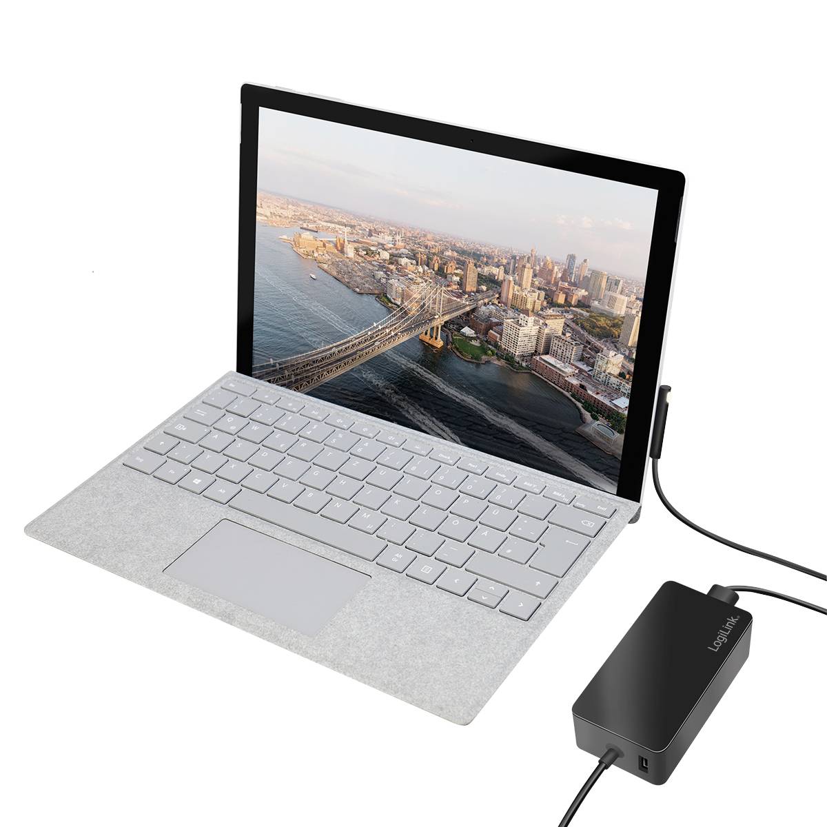 Egy laptop egy tengerparti város képével a képernyőjén csatlakoztatva van egy külső merevlemezhez.
