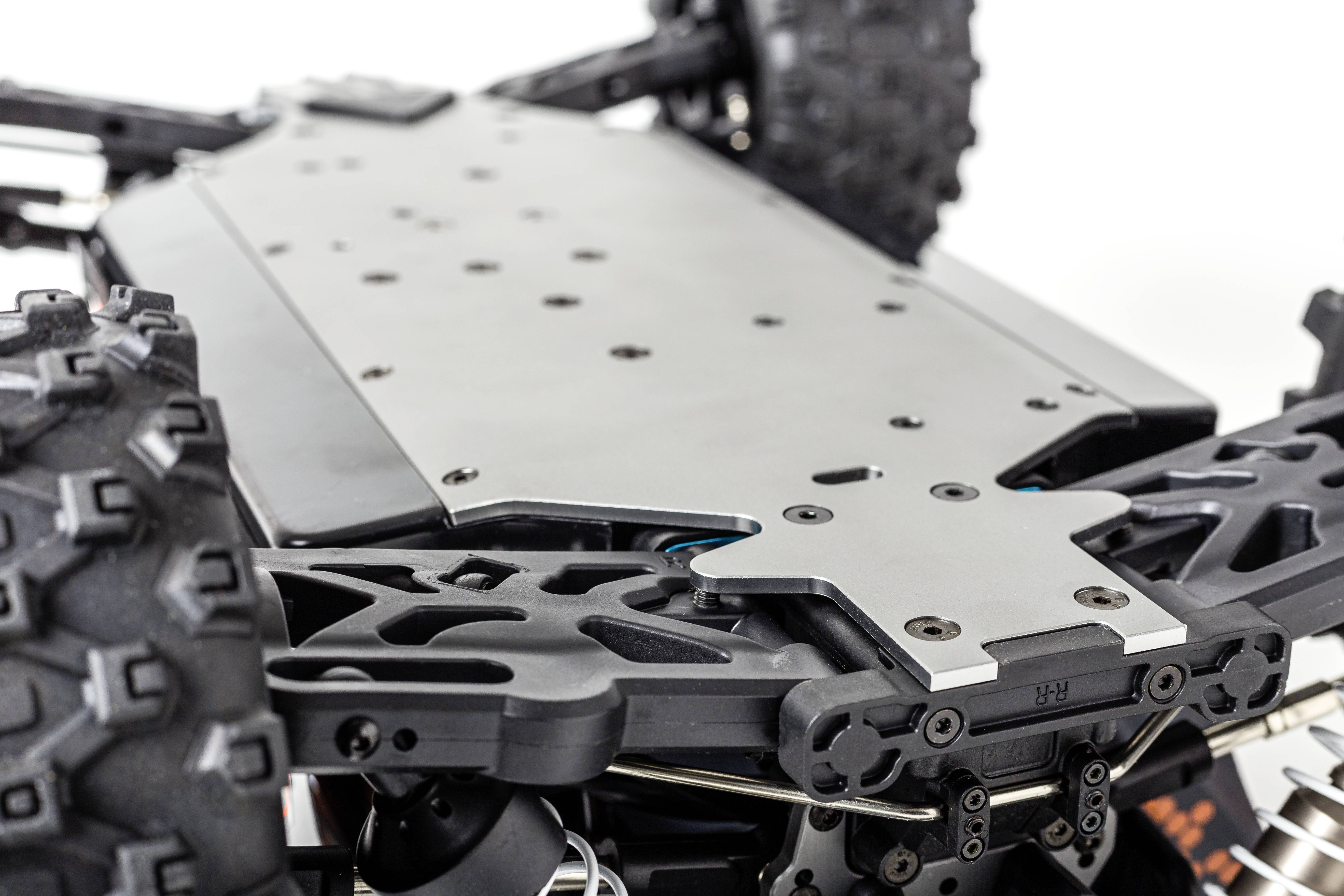 Egy távirányítós modellautó közelképe, amelyen látható az alváz. Robusztus kerekek és a futómű mechanikai részletei tűnnek fel.