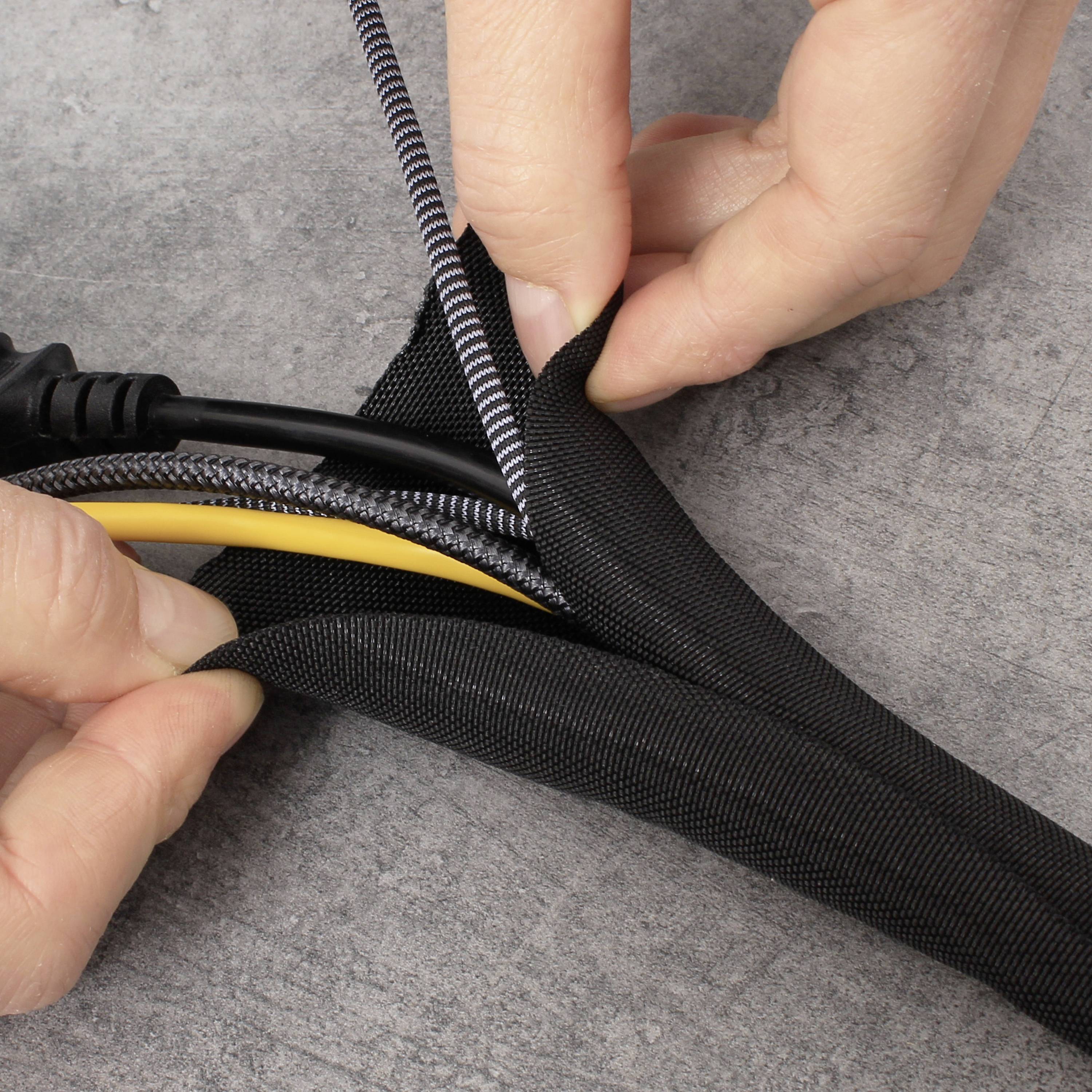 Egy személy kábeleket rendez egy fekete kábelvédő csőben, hogy azokat rendszerezze és megvédje.